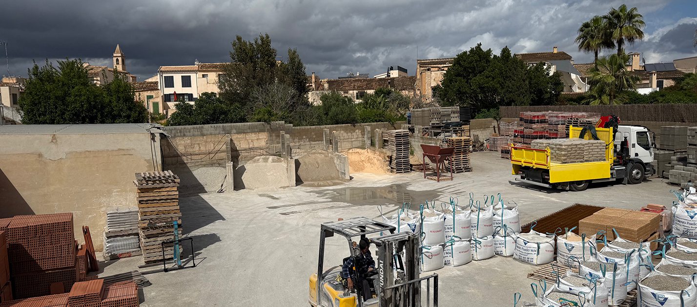 Imagen panorámica con materiales de construcción, un camión y una carretilla elevadora